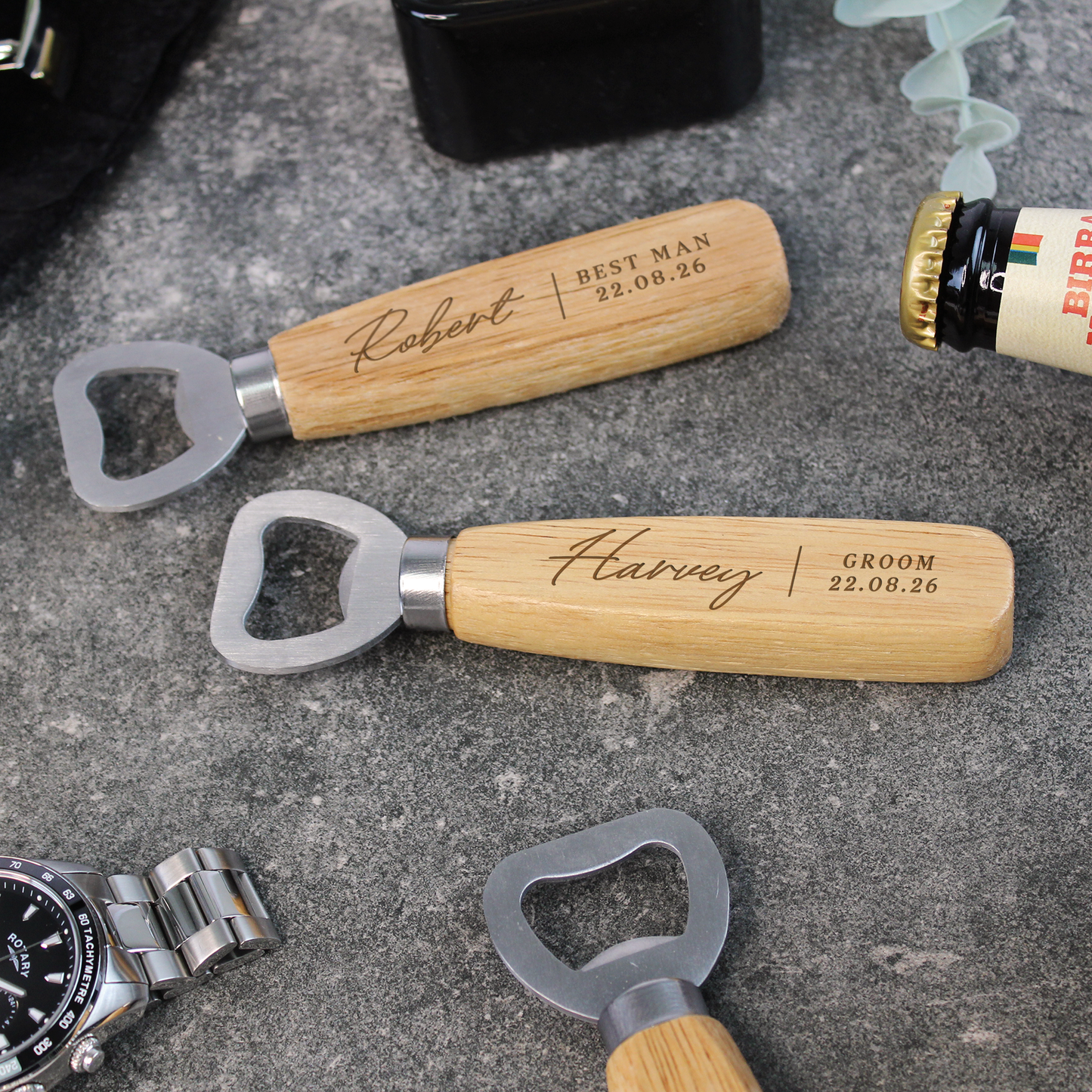 Three wooden-handled bottle openers with engraved names on a concrete surface.
