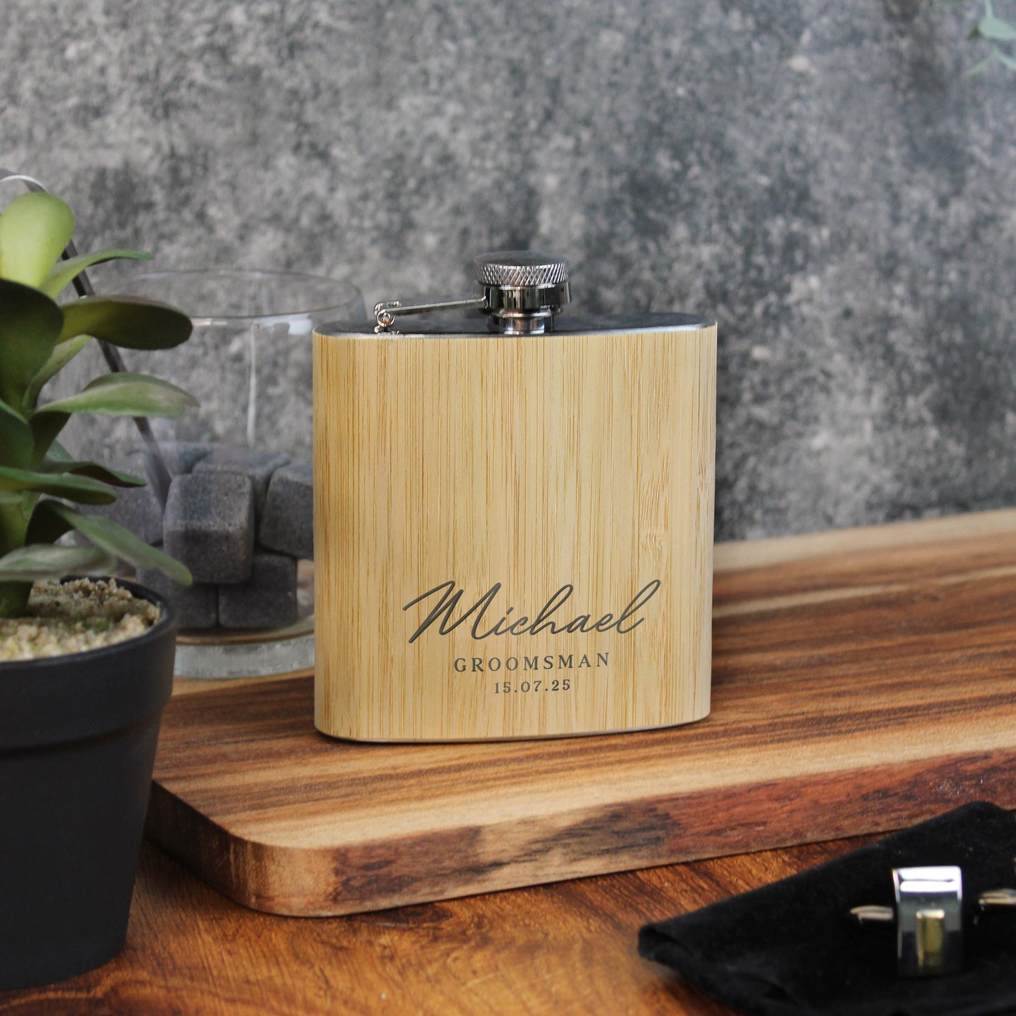 Wooden flask with engraved text on a wooden surface with a plant in the background