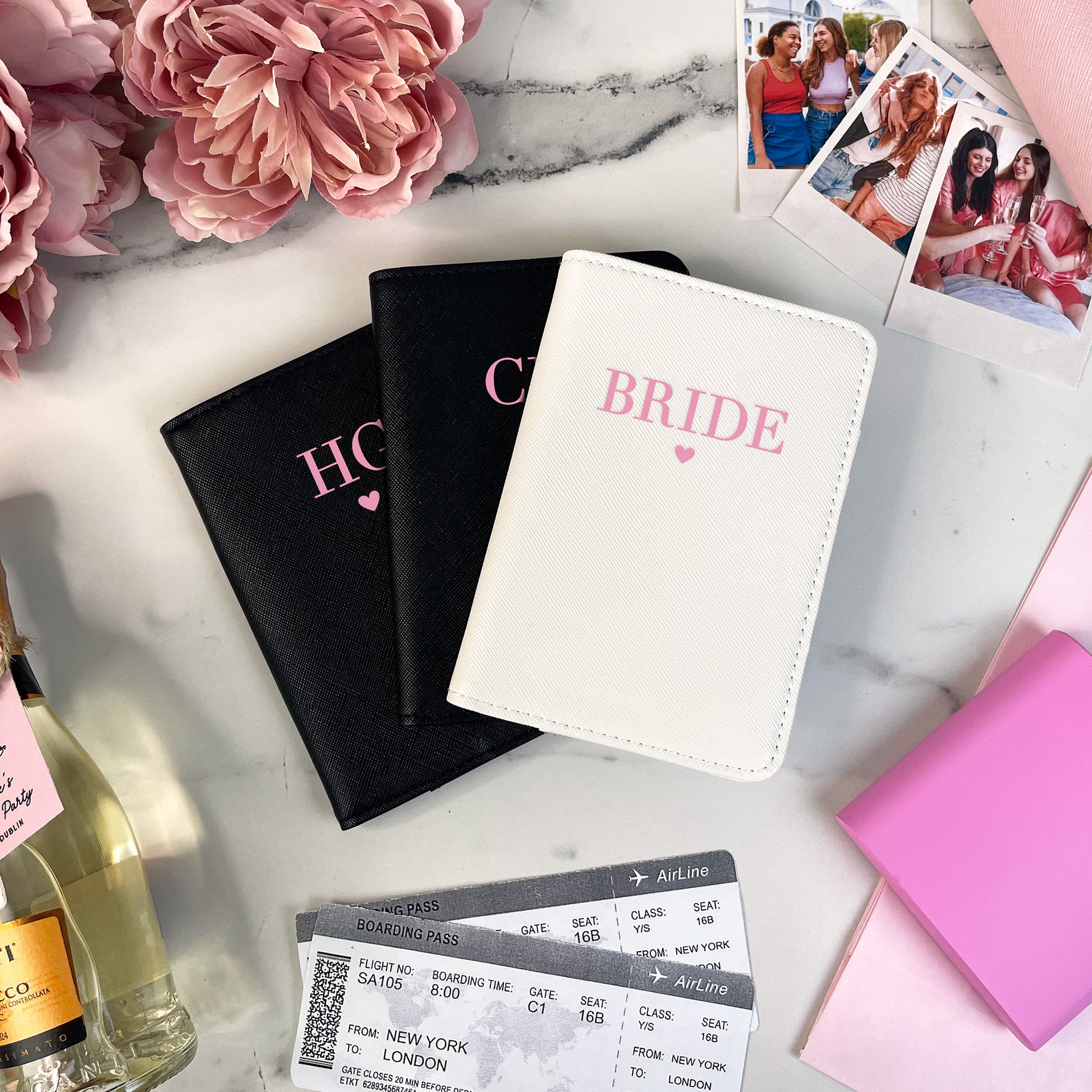Passport covers labeled 'Bride' and 'Honey' on a marble surface with flowers and a bottle of champagne.