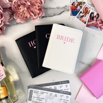 Passport covers labeled 'Bride' and 'Honey' on a marble surface with flowers and a bottle of champagne.