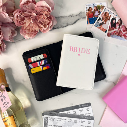 Bride wallet with cards, wine bottles, and photos on a marble surface