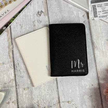 Black passport holder with 'Mr Harris' engraving on a wooden surface