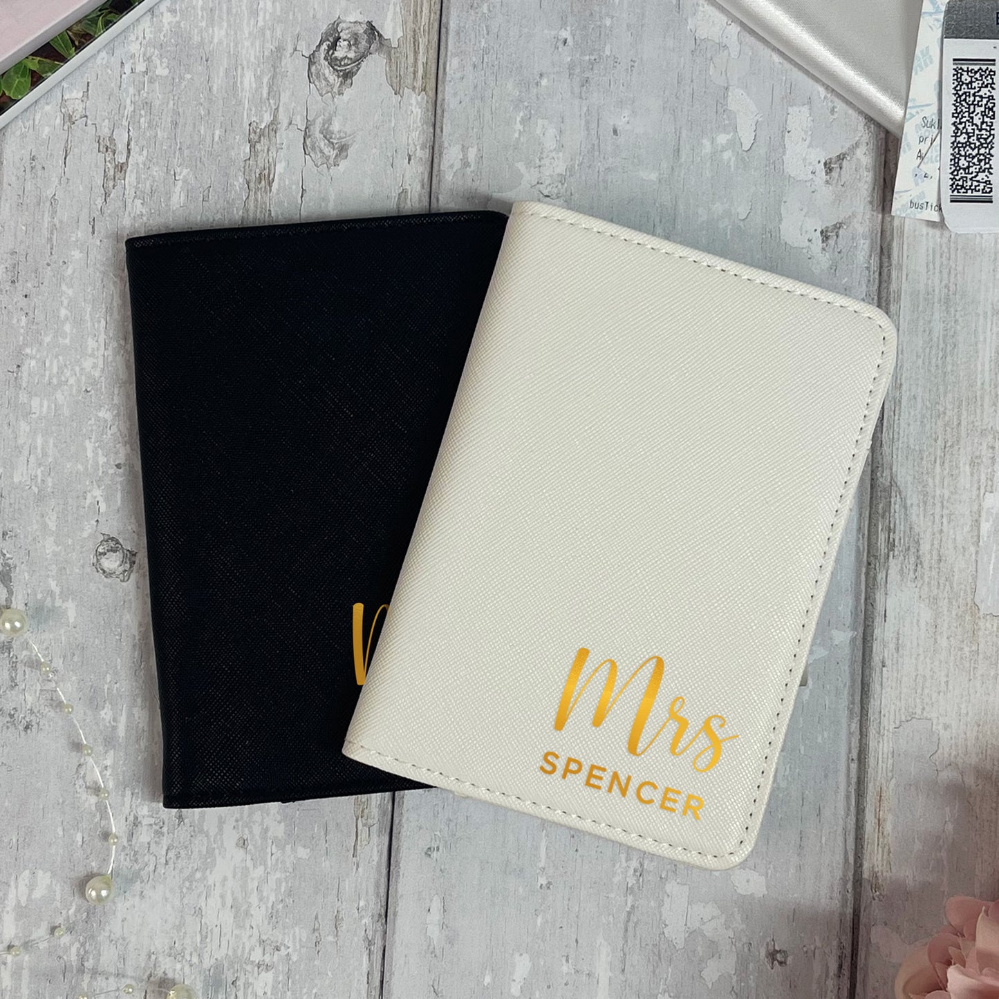 Black and white passport holders with 'Mrs Spencer' text on a wooden surface