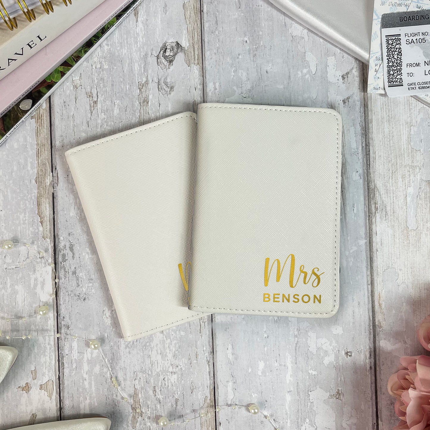 Cream-colored passport holder with 'Mrs Benson' engraving on a wooden surface.