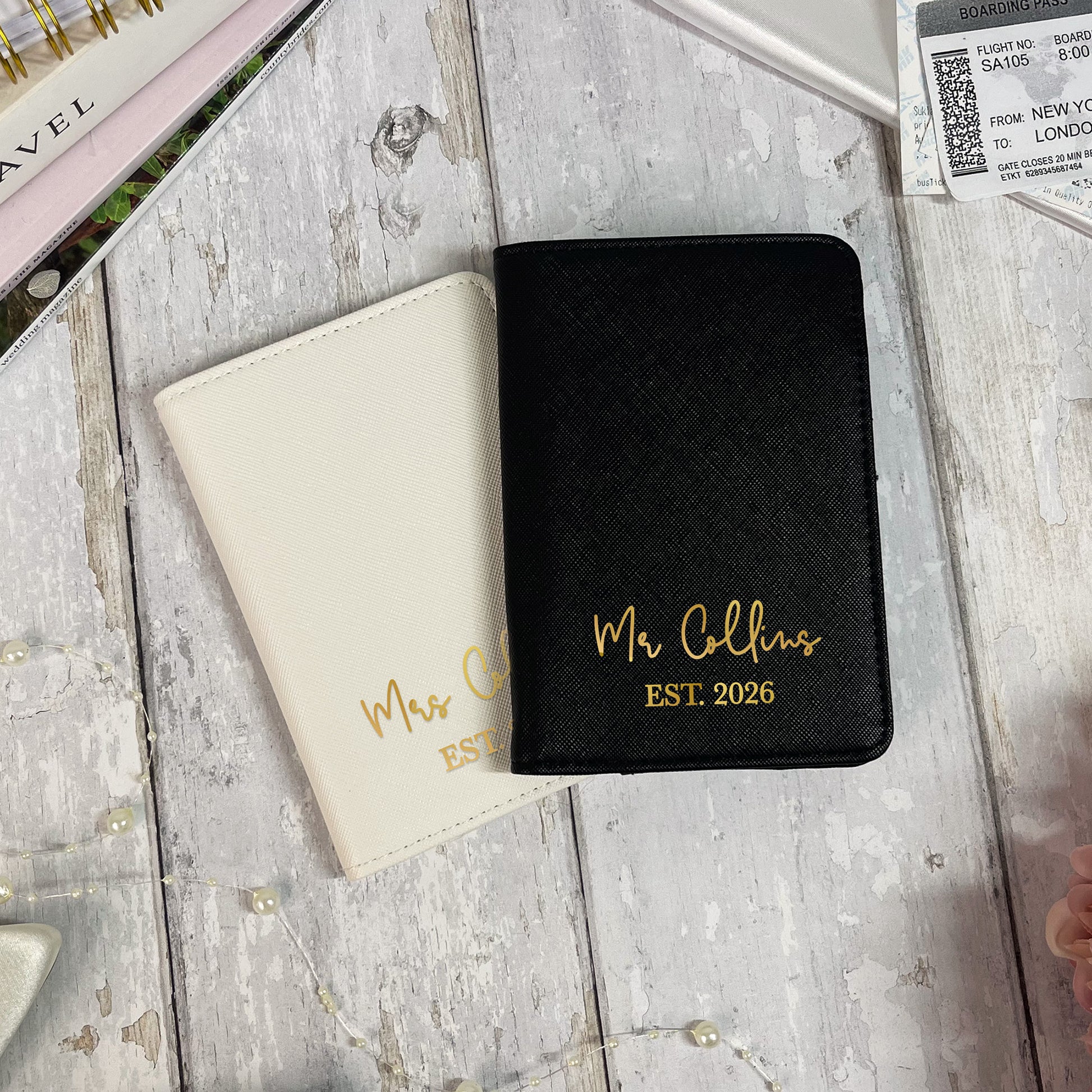 Two passport holders, one black and one beige, with 'Mr Collins EST. 2026' text on a wooden surface.