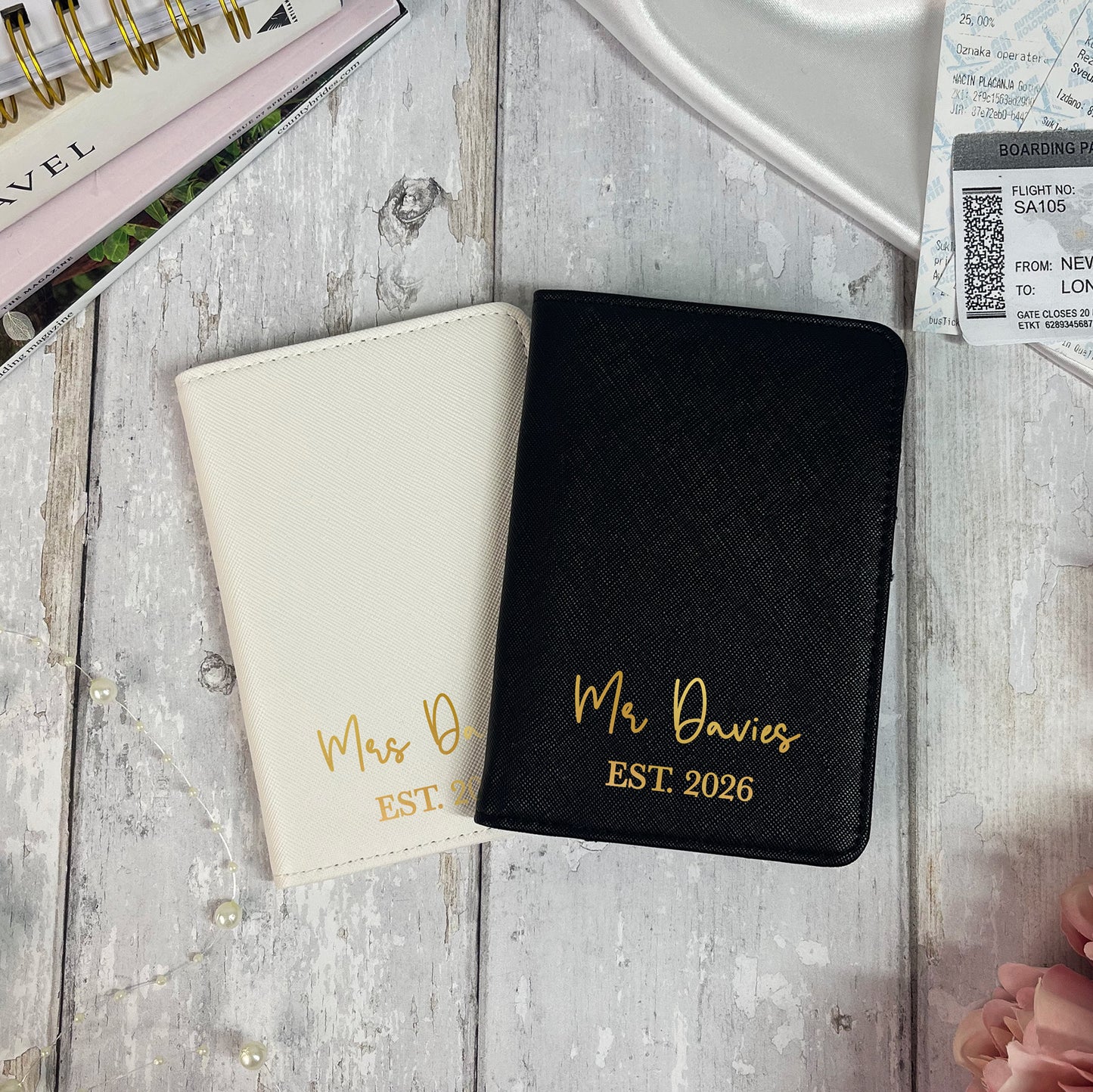 Two passport holders, one black and one beige, with personalized text on a wooden surface.