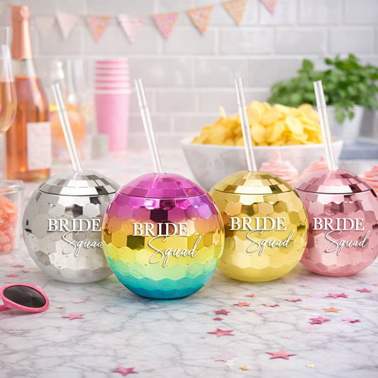 Four metallic tumblers with 'Bride Squad' text on a table with party decorations.
