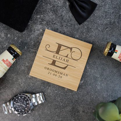 Personalized wooden coaster with engraved text on a gray surface with a watch and bottles.