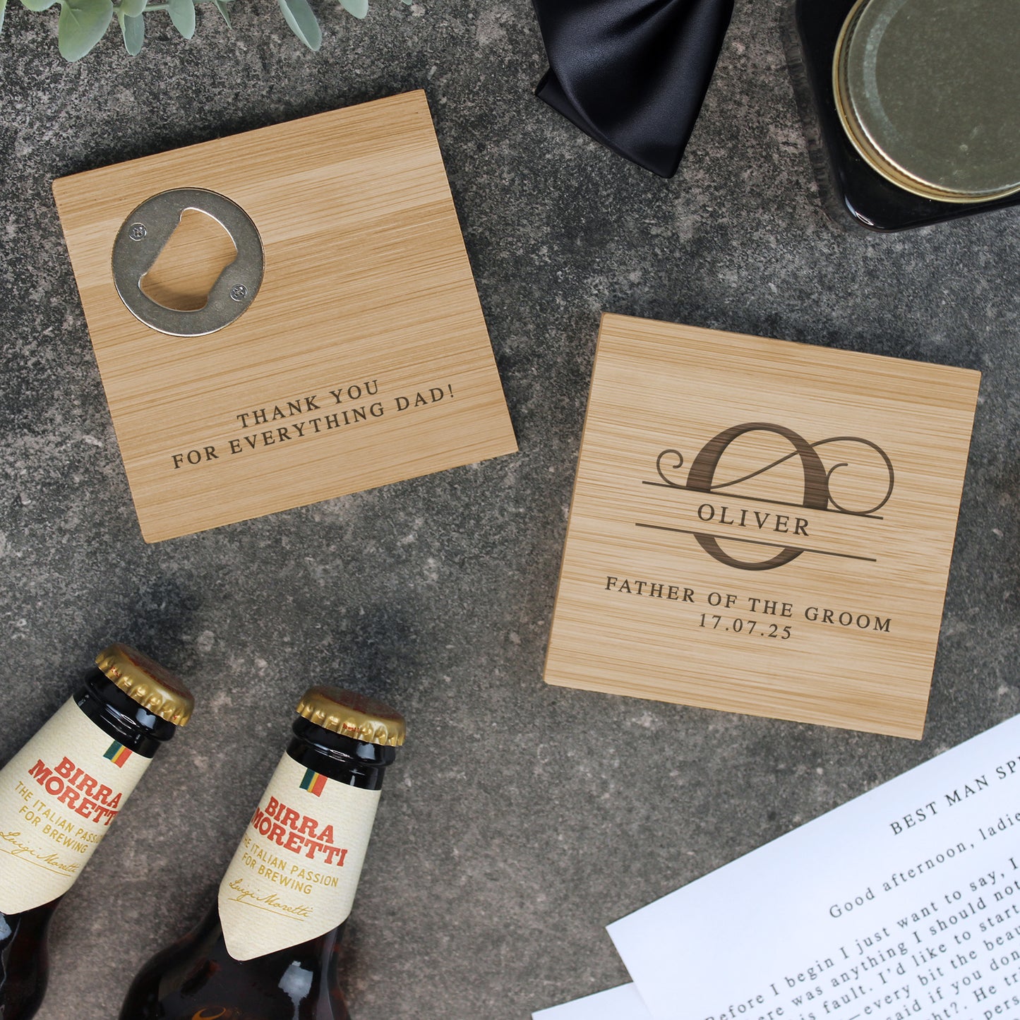 Personalized wooden coasters with engraved text on a concrete surface with bottles and stationery.