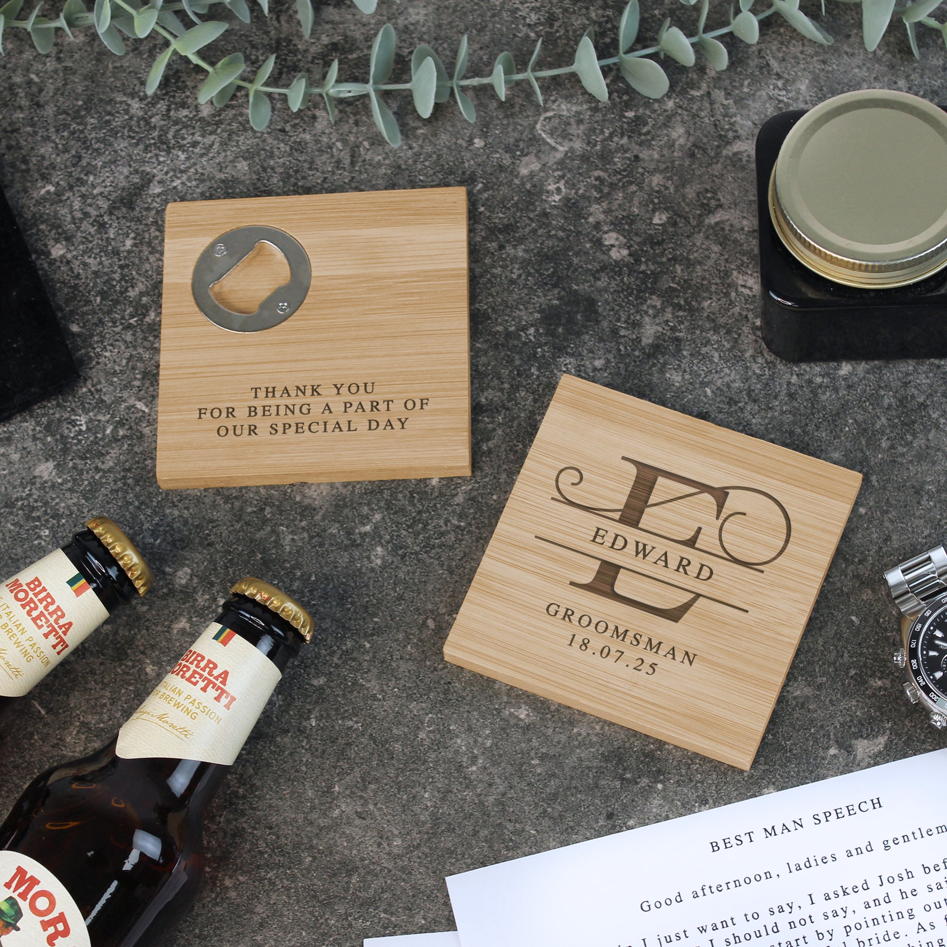 Wooden coasters with engraved text on a concrete surface with bottles and a watch.