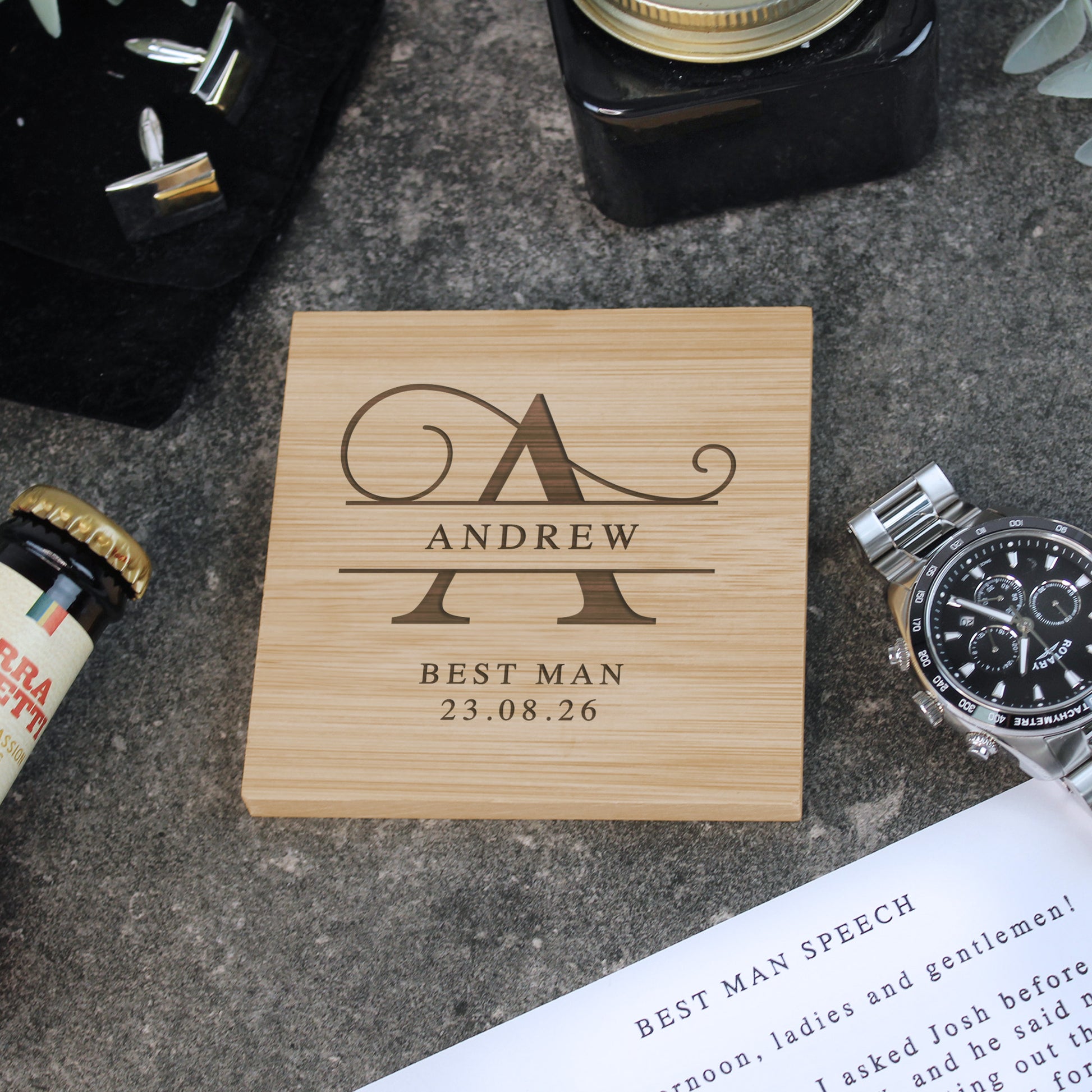 Wooden coaster with engraved name and date on a concrete surface with stationery items.
