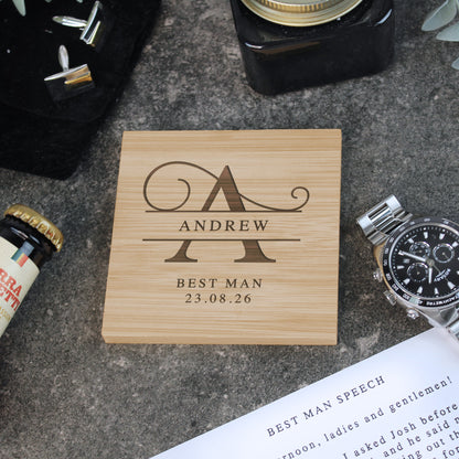 Wooden coaster with engraved name and date on a concrete surface with stationery items.