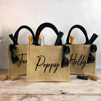 Three burlap bags with sunglasses and wine bottle holders on a wooden surface.