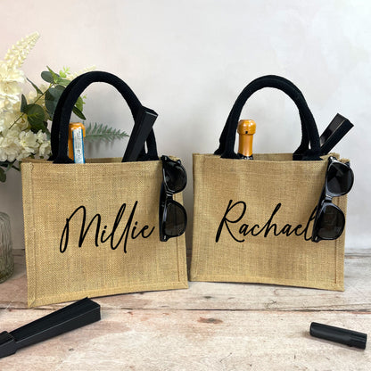 Two jute bags with personalized names 'Millie' and 'Rachael' on a wooden surface.