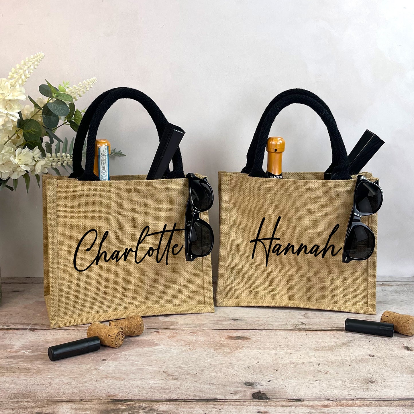 Two jute bags with 'Charlotte' and 'Hannah' branding on a wooden surface.