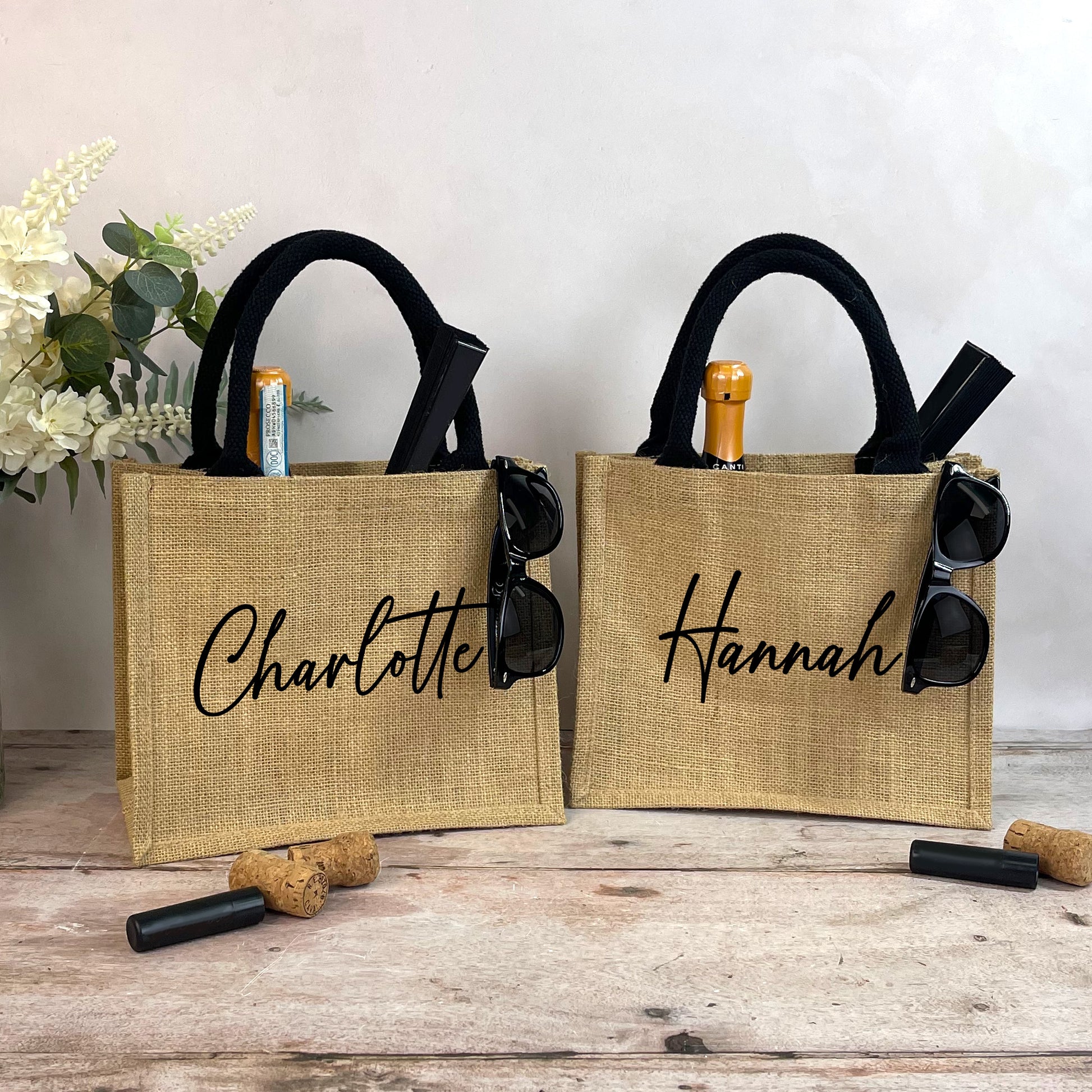 Two jute bags with 'Charlotte' and 'Hannah' branding on a wooden surface.