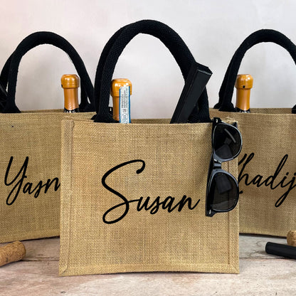 Three burlap bags with personalized names 'Yasmin', 'Susan', and 'Hadija' on a wooden surface.
