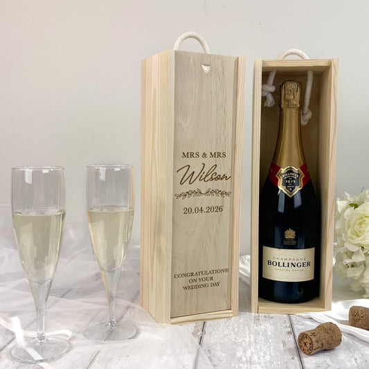 Bollinger champagne bottle in a wooden box with glasses and flowers on a light background