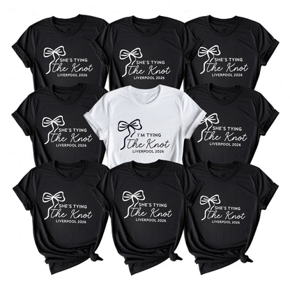 Collection of black and white t-shirts with 'She's Tying the Knot' text on a white background
