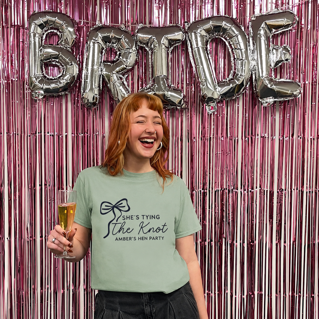 Woman holding a glass of champagne with 'Bride' balloons in the background