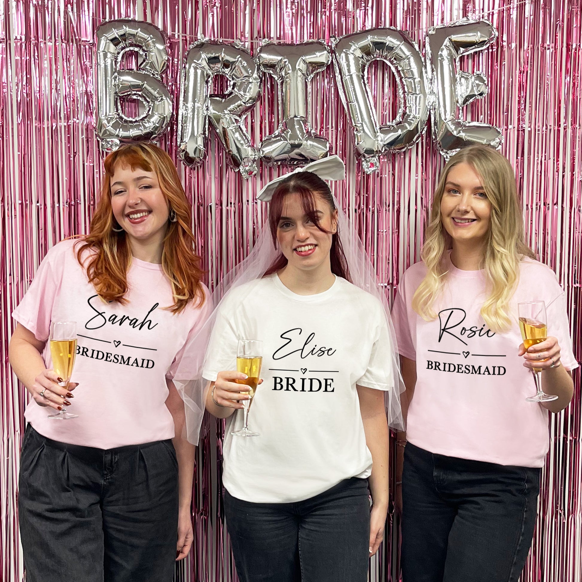 Three women in t-shirts labeled 'Bride' and 'Bridesmaid' with a 'BRIDE' balloon in the background.
