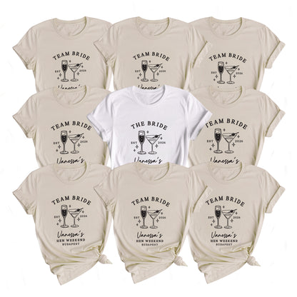 Nine short-sleeve graphic T-shirts arranged in a 3x3 grid on a white background. Eight shirts are a warm light beige/cream color and one center shirt is white.