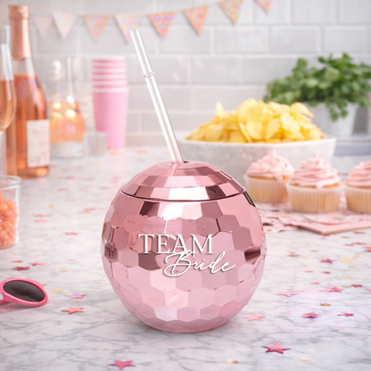 Pink disco ball tumbler with straw on a table with party decorations
